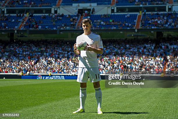 Gareth Bale poses for photographs in his new Real Madrid shirt during his official unveiling at estadio Santiago Bernabeu on September 2, 2013 in...