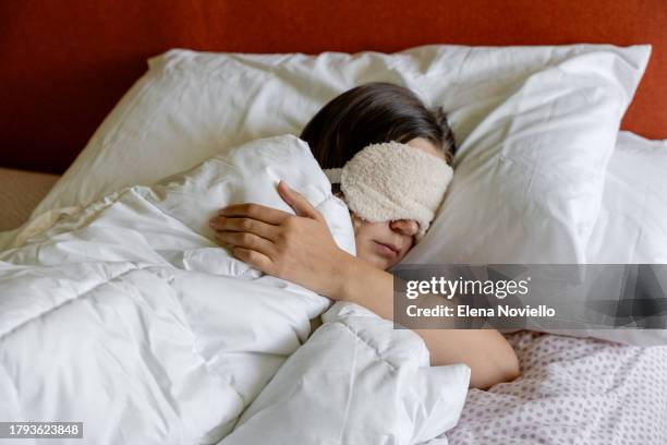 a woman sleeping with a eye sleep mask on her head - slapen stockfoto's en -beelden