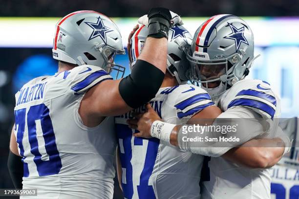 Jake Ferguson of the Dallas Cowboys is congratulated by Zack Martin and Dak Prescott after scoring a touchdown during the first half of the game...