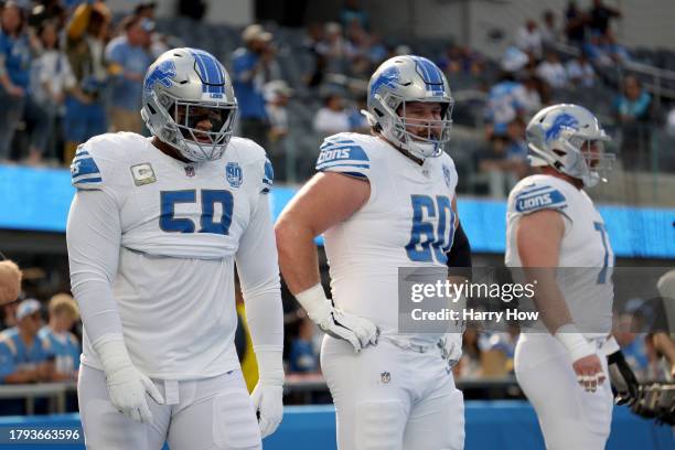 Penei Sewell, Graham Glasgow, and Frank Ragnow of the Detroit Lions look on during warm ups before the game against the Los Angeles Chargers at SoFi...