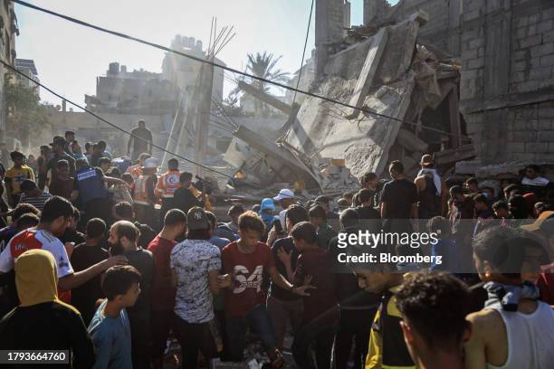 Palestinians beside the remains of a residential building destroyed by an Israeli strike in Khan Younis, Gaza, on Saturday, Nov. 18, 2023. While...