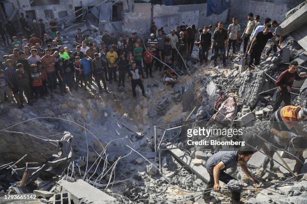 Palestinians search for casualties in the crater of a building destroyed by an Israeli strike in Khan Younis, Gaza, on Saturday, Nov. 18, 2023. While...