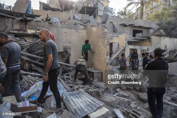 Palestinians search the remains of a residential building destroyed by an Israeli strike in Khan Younis, Gaza, on Saturday, Nov. 18, 2023. While...