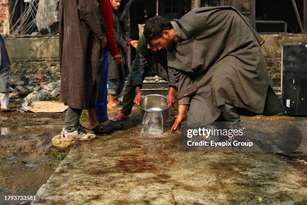 November 17 Srinagar Kashmir, India : Kashmiri villagers wash the blood stains outside a damaged house in south Kashmir's Kulgam district where five...