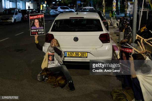People take cover as a red siren for falling rockets is heard during a rally on November 20, 2023 in Tel Aviv, Israel. Families of hostages and their...