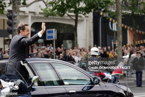 New French President Nicolas Sarkozy waves as he is driven up the Champs Elysees following a ceremony at the tomb of the unknown soldier beneath the...