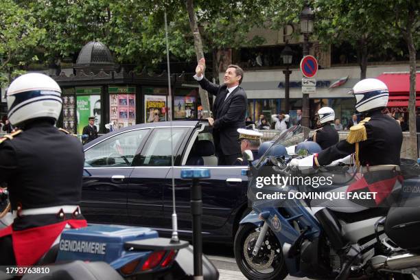 New French President Nicolas Sarkozy waves as he is driven up the Champs Elysees following a ceremony at the tomb of the unknown soldier beneath the...