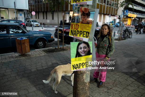 Woman walks by signs with photos of a children held hostages in Gaza Strip during a rally outside Tel Aviv's Unicef offices on Novenmber 20, 2023 in...