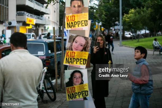 People look at signs with photos of children held hostage in Gaza Strip during a rally outside Tel Aviv's Unicef offices on Novenmber 20, 2023 in Tel...