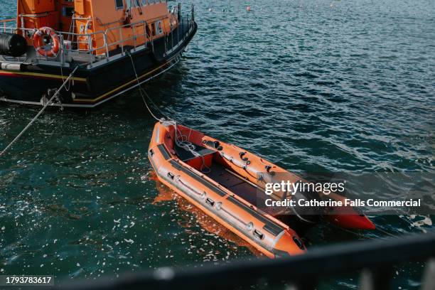 a rescue boat tugs a smaller rescue dingy behind it - coast guard stock pictures, royalty-free photos & images