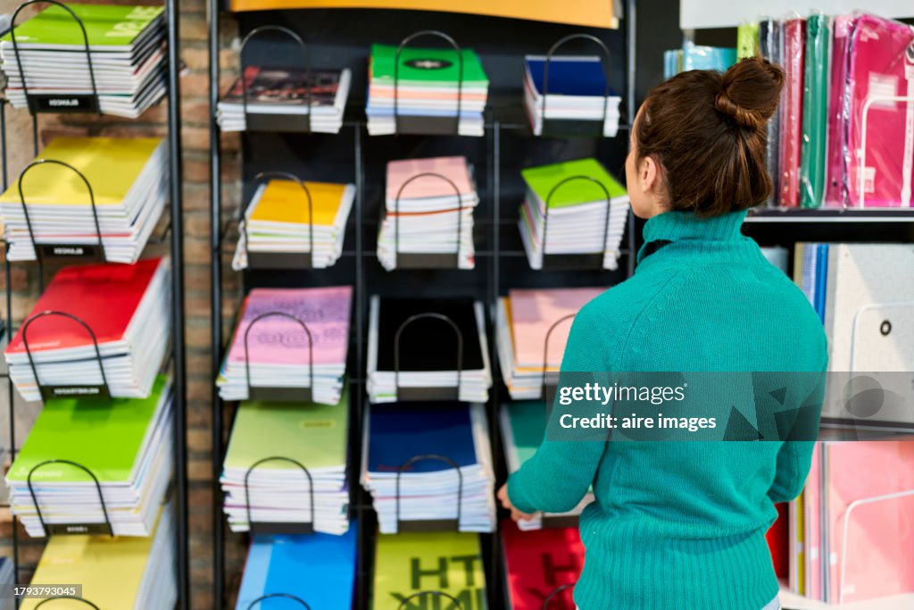Woman buying notebooks at the stationery shop. Shop and office or school supplies concept.