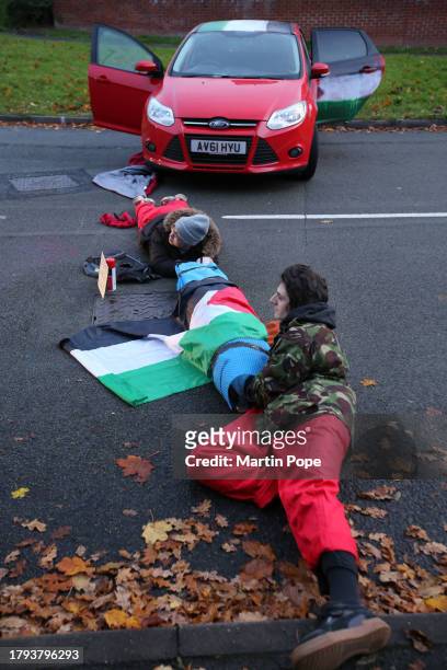 Two activists lay on the ground attached through a lock-on, blocking the road to traffic in Meridian East on November 20, 2023 in Leicester, United...