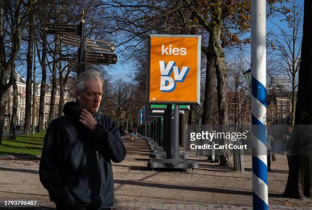 Man walks past a People's Party for Freedom and Democracy campaign poster on November 20, 2023 in The Hague, Netherlands. A snap general election is...