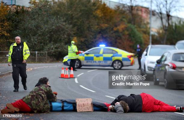 Two activists lay on the ground attached through a lock-on, blocking the road to traffic in Meridian East with a sign saying 'Shut Elbit Down' on...