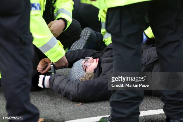 An activist is handcuffed and searched on the ground before being taken away by police officers on November 20, 2023 in Leicester, United Kingdom....