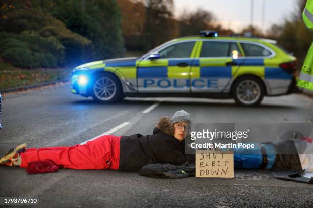 Two activists lay on the ground attached through a lock-on, blocking the road to traffic in Meridian East on November 20, 2023 in Leicester, United...