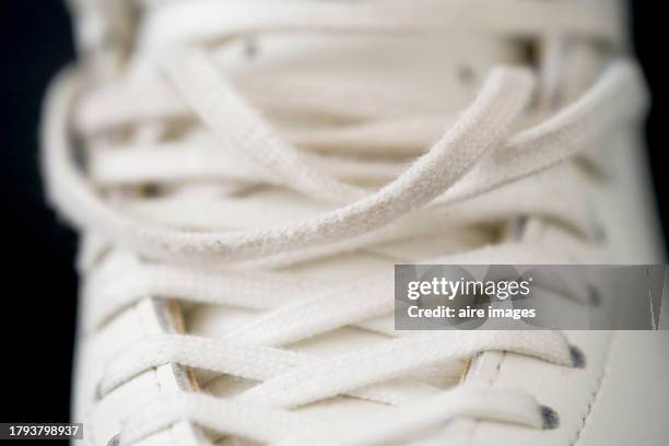 front view of white boots with loose laces on the top and black background. - black lace background stock pictures, royalty-free photos & images