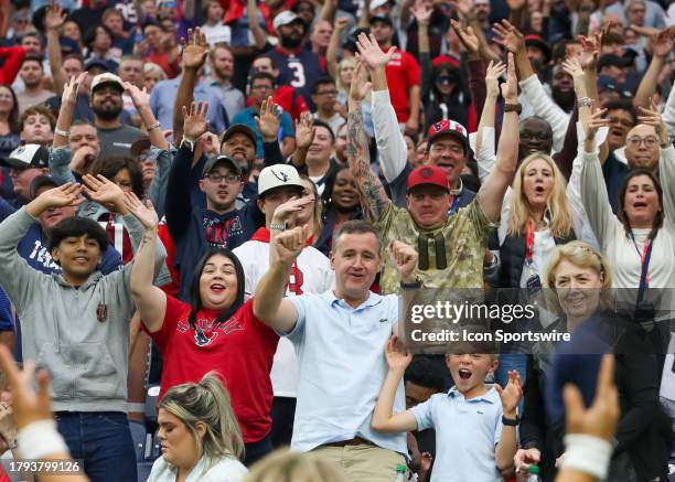 Fans wave their hands in anticipation of catching a tee shirt thrown by Houston Texans cheer squad in the third quarter during the NFL game between...