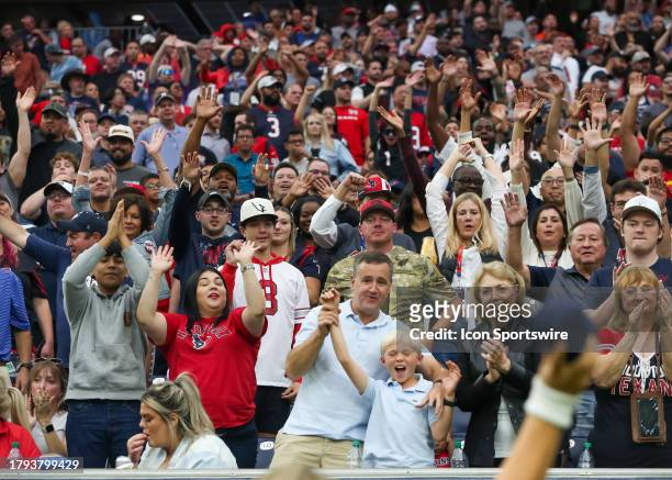 Fans wave their hands in anticipation of catching a tee shirt thrown by Houston Texans cheer squad in the third quarter during the NFL game between...