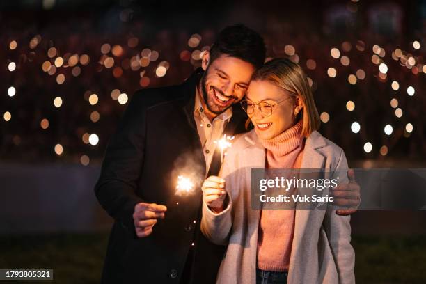 pareja sosteniendo destellos - new year fotografías e imágenes de stock
