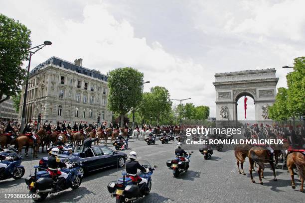 French President Nicolas Sarkozy waves from his car, 16 May 2007, as he drives up the Champs-Elysees avenue in Paris in an open-top car, escorted by...