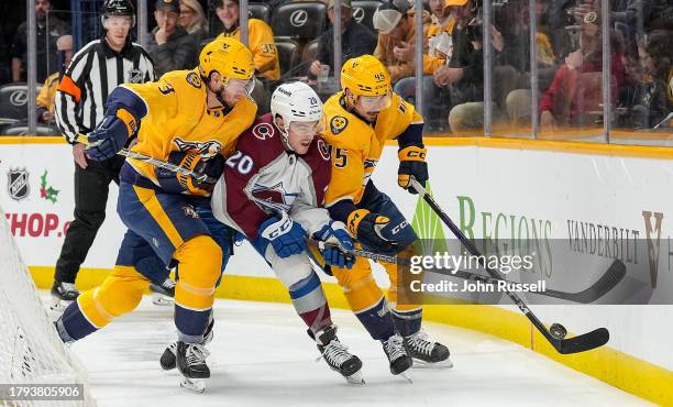 Ross Colton of the Colorado Avalanche battles for the puck against Jeremy Lauzon and Alexandre Carrier of the Nashville Predators during an NHL game...