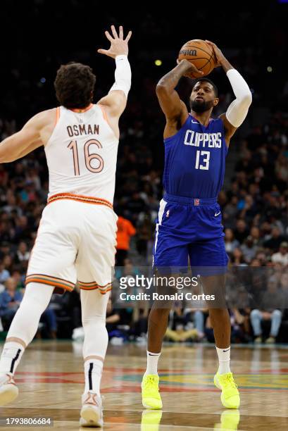 Paul George of the Los Angeles Clippers shots over Cedi Osman of the San Antonio Spurs in the first half at Frost Bank Center on November 20, 2023 in...