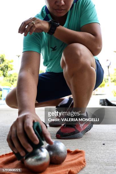 This photo taken on November 8, 2023 shows a player cleaning a petanque ball after training at a petanque court in Bangkok. Half a world away from...