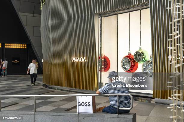 Shopper sits in front of a Prada SpA store on Orchard Road in Singapore, on Monday, Nov. 20, 2023. Singapore's gross domestic product figures for the...