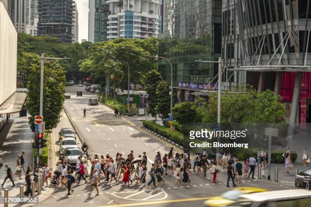 Pedestrians cross a road on Orchard Road in Singapore, on Monday, Nov. 20, 2023. Singapore's gross domestic product figures for the third quarter are...