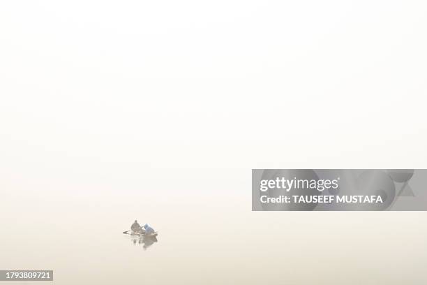 Man rows a boat amid dense fog in the Dal Lake in Srinagar on November 21, 2023.