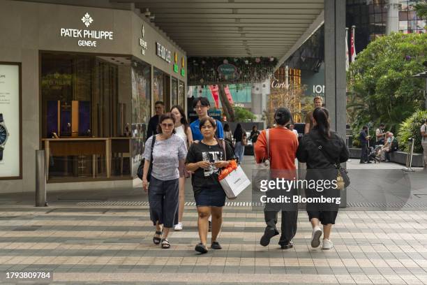 Pedestrians cross a road in front of a Patek Philippe SA store on Scotts Road in Singapore, on Monday, Nov. 20, 2023. Singapore's gross domestic...