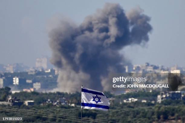 This picture taken from the border with the Gaza Strip shows a national flag on the Israeli side as smoke billows during an Israeli strike on the...