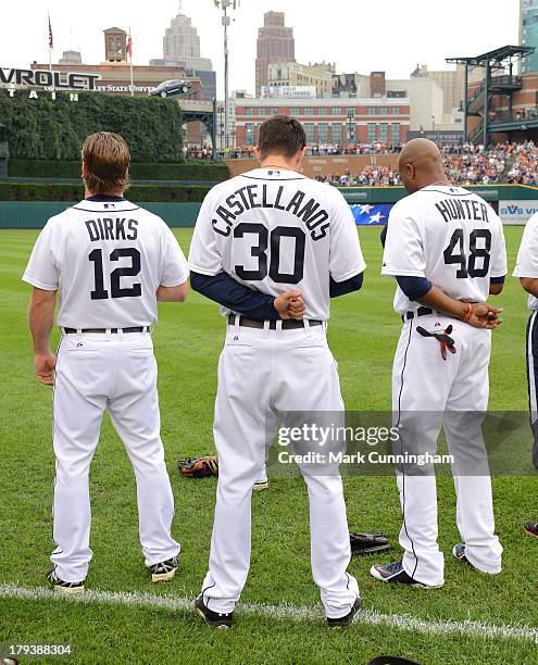 Andy Dirks, Nick Castellanos and Torii Hunter of the Detroit Tigers stand together on the field during the National Anthem prior to the game against...