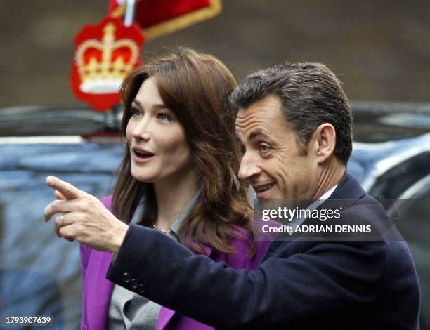 French President Nicolas Sarkozy points towards the door of 10 Downing Street as he arrives with his wife Carla Bruni-Sarkozy for a meeting with...