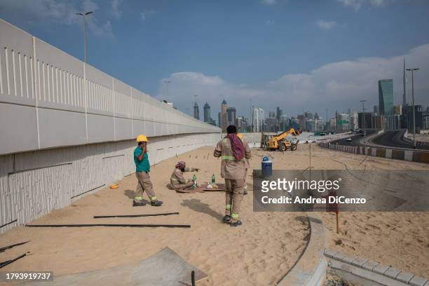 Workers take a break from gardening along side a freeway on October 26, 2023 in Dubai, United Arab Emirates. The Dubai Municipality is working to...