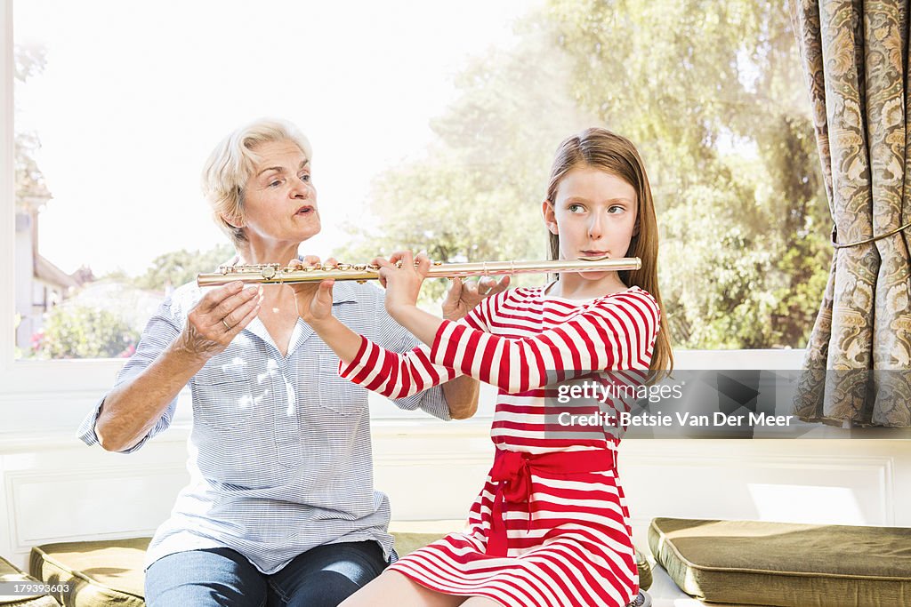 Grandmother teaching grandchild playing flute.