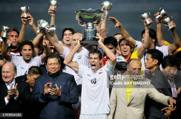 Iraqi captain Younis Mahmoud holds up the winning trophy as his team members celebrate while Indonesian President Susilo Bambang Yudhoyono looks on...