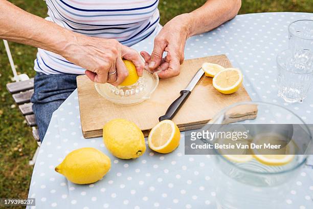 close up of mature woman making lemonade. - saftpresse stock-fotos und bilder