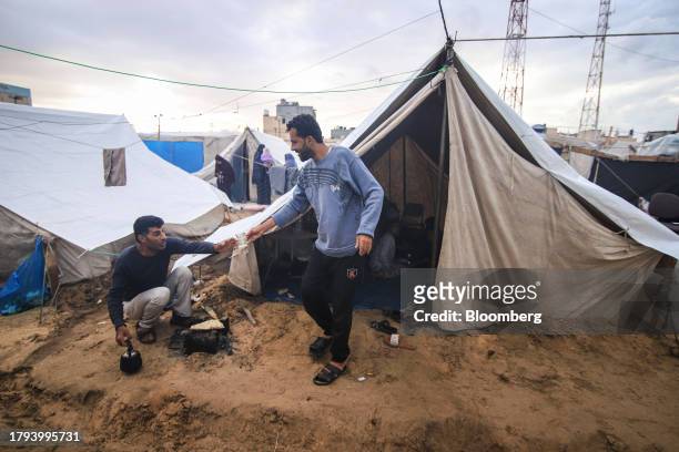 Displaced Palestinians warm bread on a stove outside a temporary shelter at a camp, operated by the United Nations Relief and Works Agency , in Khan...