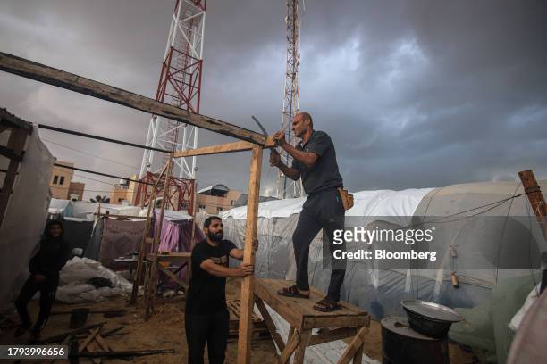 Displaced Palestinians build a structure for a temporary shelter at a camp, operated by the United Nations Relief and Works Agency , in Khan Younis,...