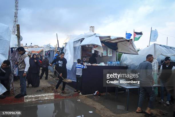 Palestinian man shifts earth to build a pathway across rain puddles in a temporary camp, operated by the United Nations Relief and Works Agency , in...