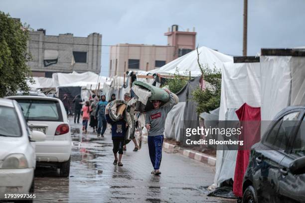 Displaced Palestinians carry bedding materials at a camp, operated by the United Nations Relief and Works Agency , in Khan Younis, Gaza, on Sunday,...
