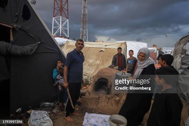 Displaced Palestinians use a mud oven to prepare food beside temporary shelters at a camp, operated by the United Nations Relief and Works Agency ,...