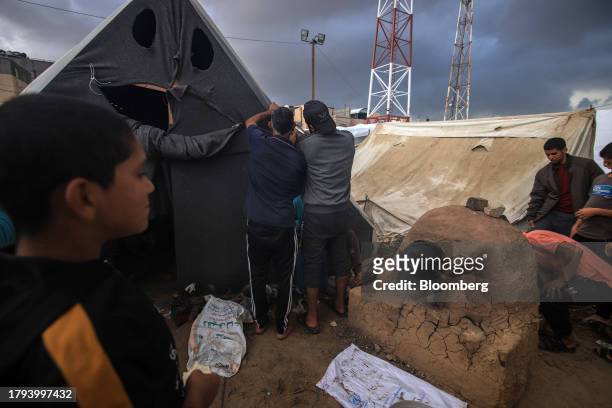 Displaced Palestinians prepare a temporary shelter beside a mud oven at a camp, operated by the United Nations Relief and Works Agency , in Khan...