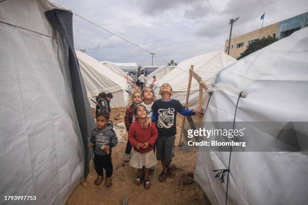 Displaced Palestinian children pose for the camera outside temporary shelters at a camp, operated by the United Nations Relief and Works Agency , in...