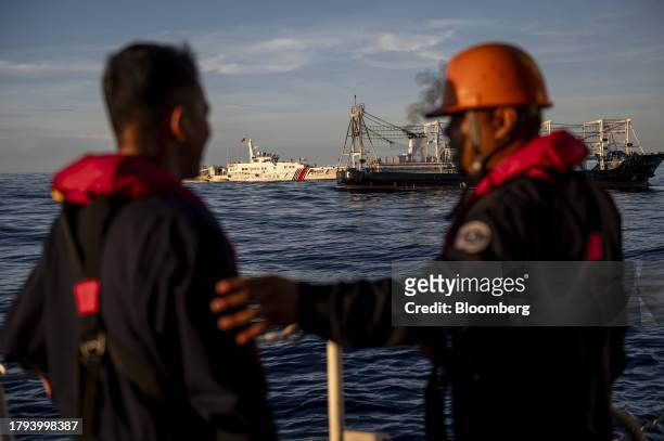 Philippine Coast Guard personnel look at a China Coast Guard ship and a Chinese fishing vessel, which Manila calls maritime militia vessel, during a...