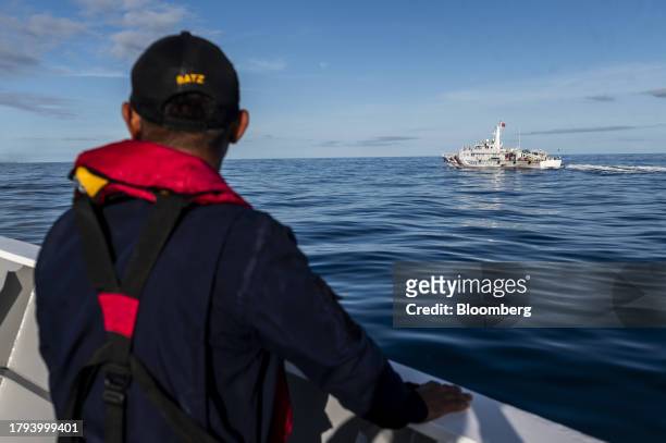 Philippine Coast Guard personnel looks out at a China Coast Guard ship during a resupply mission for the BRP Sierra Madre, in the Second Thomas Shoal...
