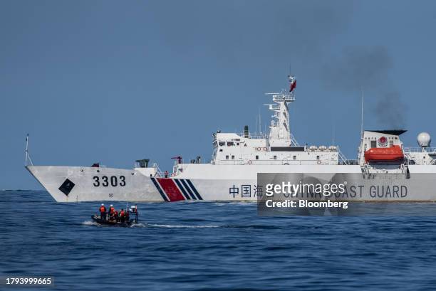 Rigid-hulled inflatable boat carrying Philippine Coast Guard personnel and members of the media moves past a China Coast Guard ship during a resupply...
