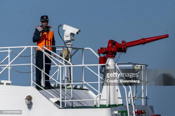 China Coast Guard personnel holds a video camera pointed at a Philippine Coast Guard ship during a resupply mission for the BRP Sierra Madre, in the...